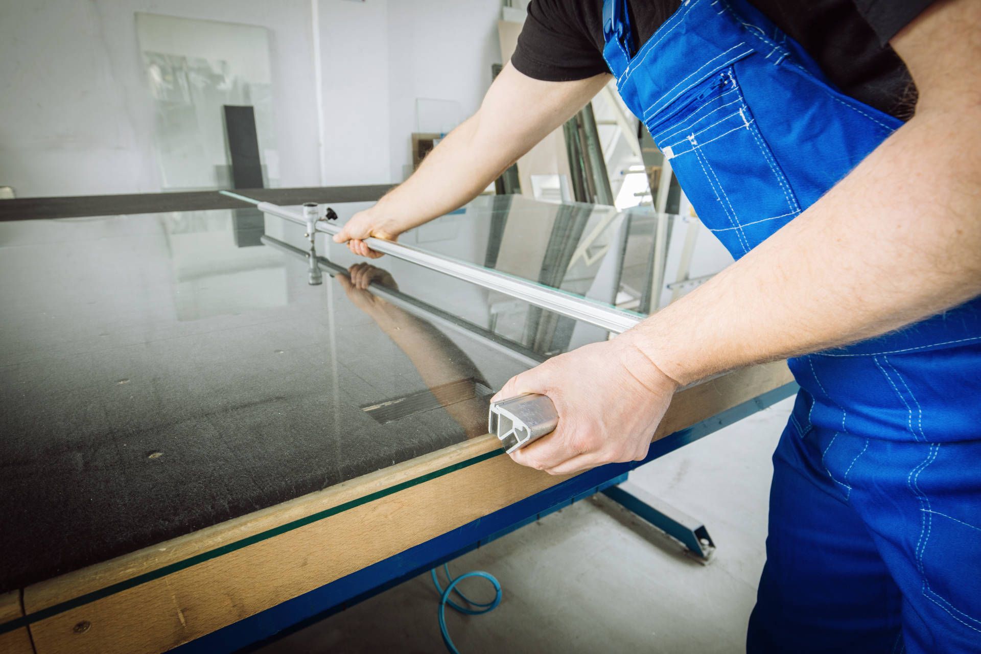 Glazier cutting glass on table
